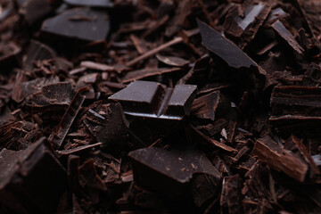 Tasty crushed dark chocolate as background, closeup