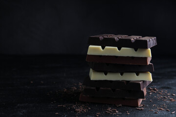 Different tasty chocolate bars on black table. Space for text