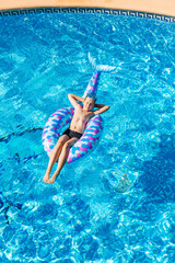 Boy relaxing on air mattress in the swimming pool