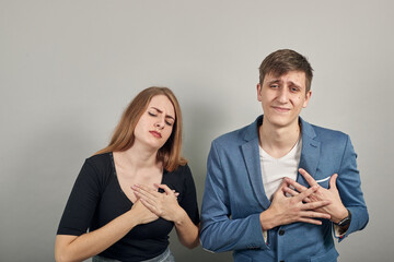 Chest pain can have a variety of causes, heart attack, major health. Young attractive couple boyfriend girlfriend two people, dressed black t-shirt, blue jacket, grey background