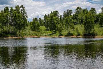 Lake in the mountain with wavy blue water and green meadow with forest on a cloudy weather summer day. Travel, tourism, and resort in nature concept. Vlasina lake, Serbia, Europe.