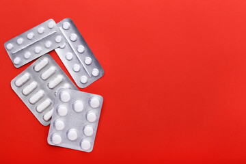 White pills in blisters on red background