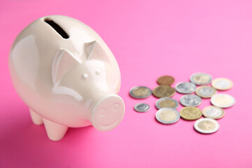 Piggybank with coins on pink background
