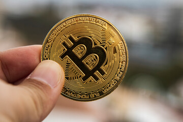 Fingers of a hand holding a bitcoin