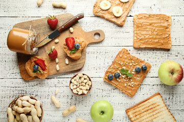 Bread with peanut butter, fruits and nuts on white wooden table