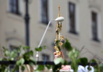 Golden monstrance shown by priest during Corpus Christi celebrating in street, in background buildings