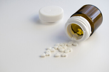 Pills  group are on the table. Brown plastic jar is near pills.  Closeup, white background, top...