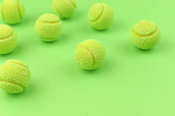 Chewing gum in the shape of a tennis ball on the green background. Harm to teeth. Place for text.