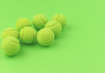 Chewing gum in the shape of a tennis ball on the green background. Harm to teeth. Place for text.