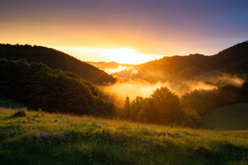 epic summer panorama of foggy sunset in mountains
