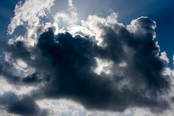 thundercloud with sunbeams on a background of blue sky