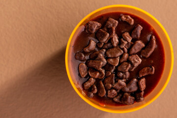 acrylic cup with brigadeiro and chocolate sprinkles on brown background