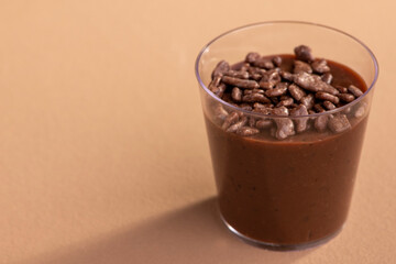 acrylic cup with brigadeiro and chocolate sprinkles on brown background