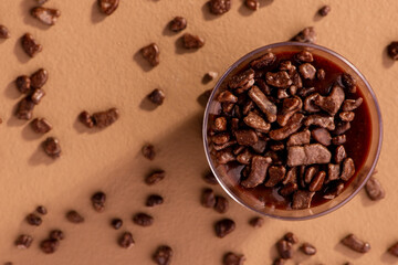 acrylic cup with brigadeiro and chocolate sprinkles on brown background