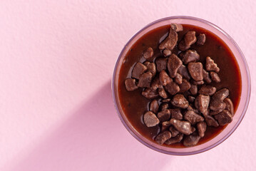 acrylic cup with brigadeiro and chocolate sprinkles on lilac background