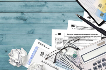 IRS form 990 Return of organization exempt from income tax lies on flat lay office table and ready...