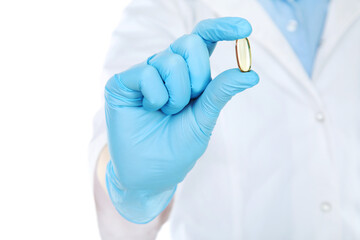 Doctor hand in glove holding capsule on white background