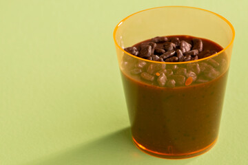 acrylic cup with brigadeiro and chocolate sprinkles on green background