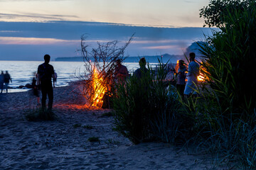 Large crowd of unrecognisable people celebrating summer solstice with large bonfires on Baltic Sea sandy beach