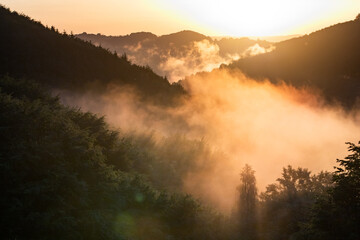 epic summer panorama of foggy sunset in mountains