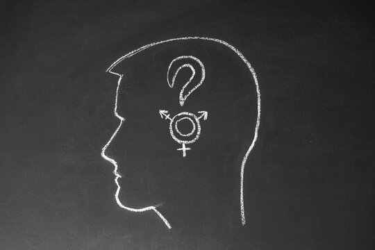 Concept man thinks about gender. Male head, question mark and gender symbols drawn on a chalk board.