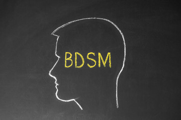Concept man thinks about BDSM. Male head and the inscription BDSM on the chalk board.