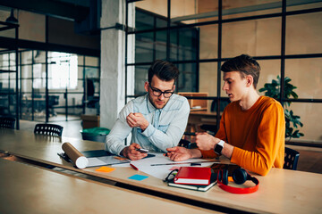 Experienced male architects working on project in collaboration sharing ideas and opinions during productive job, young students planning common coursework brainstorming discussing creative solutions