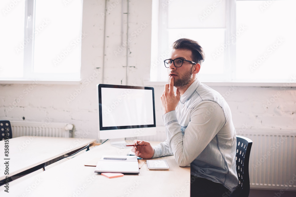 Poster caucasian serious male it developer pondering on false on website while sitting at desktop with comp