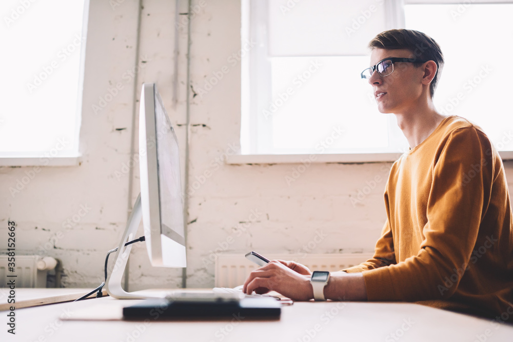 Poster thoughtful caucasian male it developer pondering on creating website sitting with modern computer on