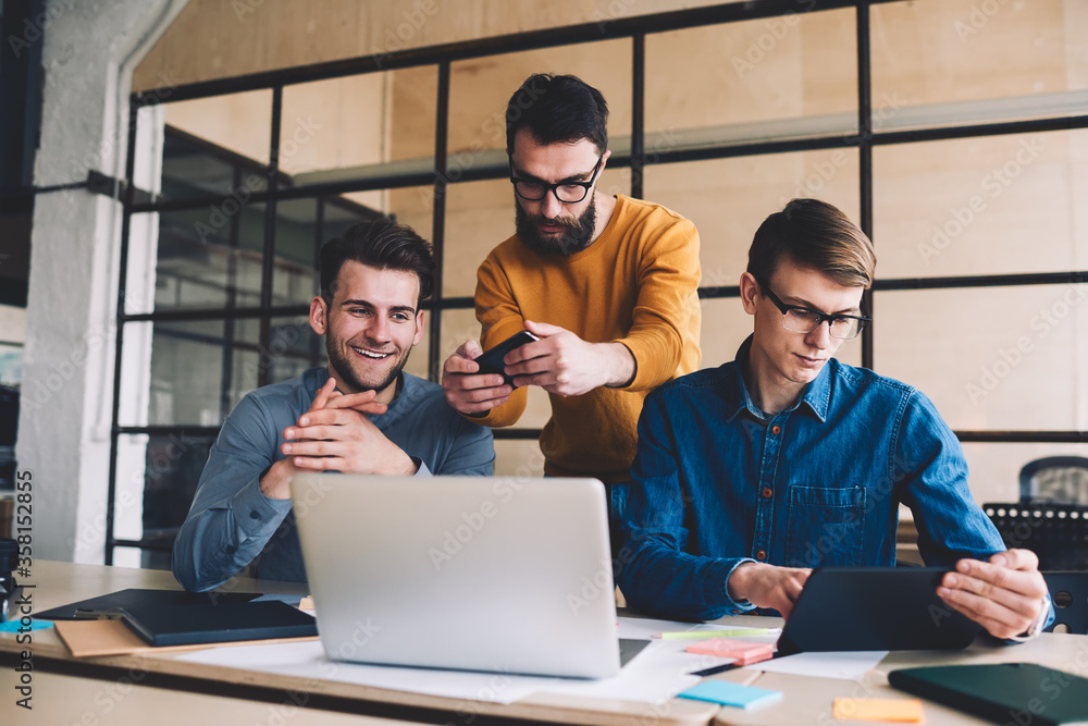 Aufkleber millennial hipster guys collaboration together in coworking space sitting at desktop with laptop whi