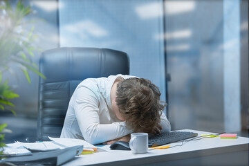 A young tired office worker in put his head on the table from fatigue.