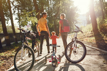 Family in a park. People with a bicycle. Parents with little daughter.