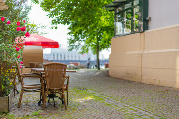 wooden chairs and tables in a  pedestrian area in front of a coffee