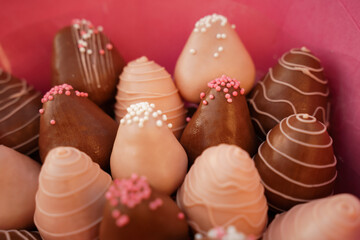 Luxury chic surprise gift for a girl, a bouquet of strawberries with chocolate in pink gift wrapping paper. Strawberries in white and dark chocolate, decorated with balls and stripes. The concept of a