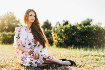 Full length portrait of beautiful woman with long curly hair on currant field background. Girl in a...