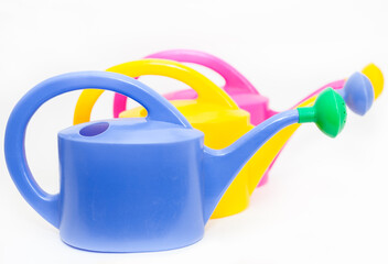 Blue, yellow and pink watering cans with shower nozzles, white background © Kekyalyaynen