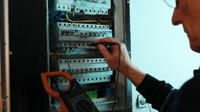 Electricians hands testing current  electric in control panel. Electrician engineer work  tester measuring  voltage and current of power electric line in electical cabinet control.