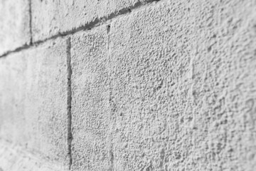Plastered gray wall of the building, imitation of slabs and bricks. Black and white photo