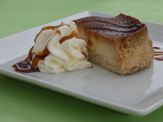 Flan - one of the most popular desserts in Spain and other countries, served on a square white plate with whipped cream and caramel sauce