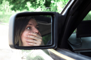 Girl driver scared driving a car. scared face of a girl in a side mirror of a car. 