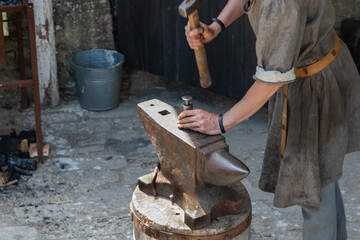 Man hitting the stuff on anvil with hammer