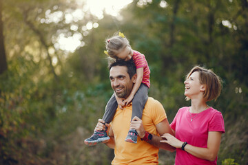 Fototapeta premium Family with cute little daughter. Father in a yellow t-shirt. People walks in a park.