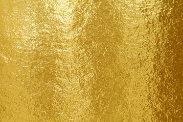 Gold foil texture background with highlights and uneven surface