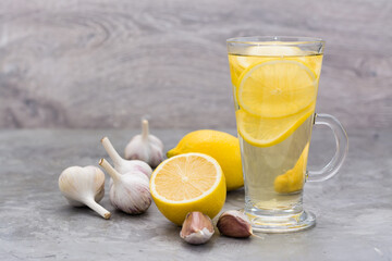 Therapeutic drink of lemon and garlic in a glass on the table. Alternative medicine