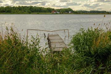 View through the reeds to the old fishing bridge. A lake used by many townspeople for a weekend break near the village.