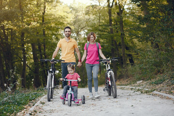 Family in a park. People with a bicycle. Parents with little daughter.