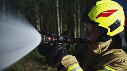 Portrait shot of the firefighter spraying fire with the hose. Close up. High quality photo