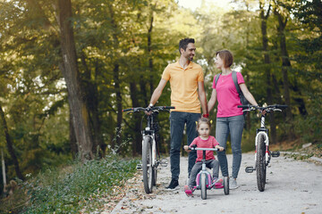 Family in a park. People with a bicycle. Parents with little daughter.