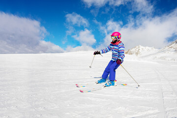 Fototapeta na wymiar Alpine ski portrait of a girl in colorful sport outfit going downhill
