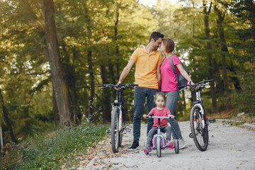 Obraz premium Family in a park. People with a bicycle. Parents with little daughter.